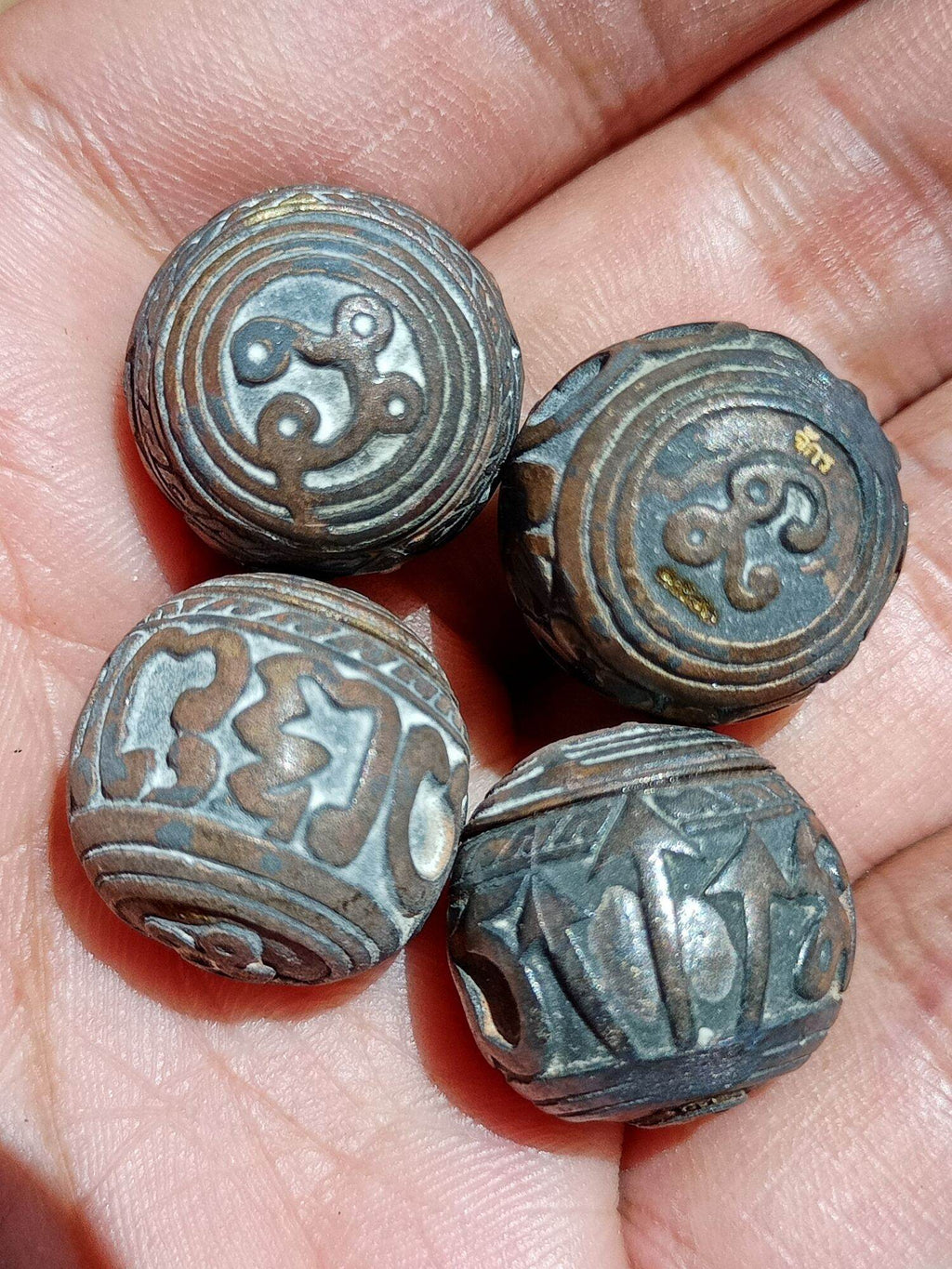 Set of four engraved metal round sacred bullet amulet Thailand beads with yantra designs in hand