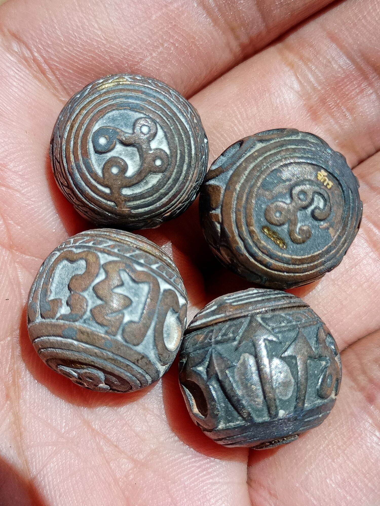 Set of four engraved metal round sacred bullet amulet Thailand beads with yantra designs in hand