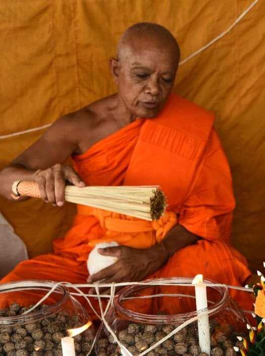 Thai monk blessing sacred bullet amulet Thailand on table with candles during ritual ceremony