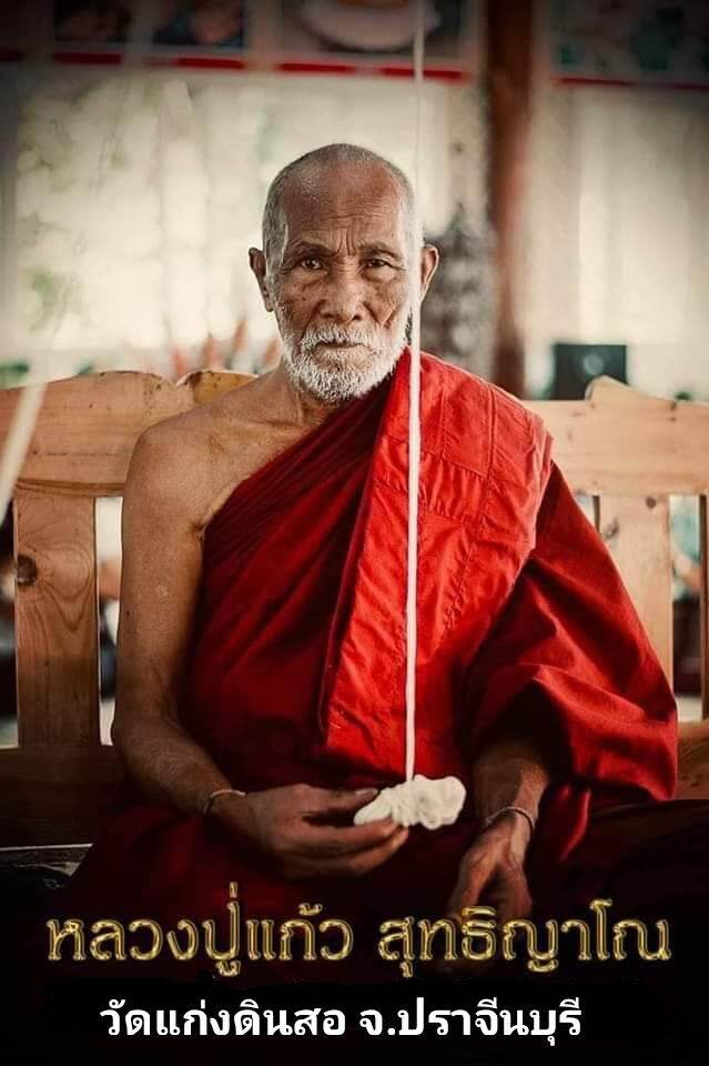 Thai monk holding a temple amulet pendant on string Thai Blessing Co sacred protection charm for fortune