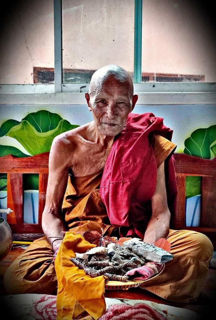 Thai monk holding tray of amulets and a sacred protection charm for fortune displayed by Thai Blessing Co