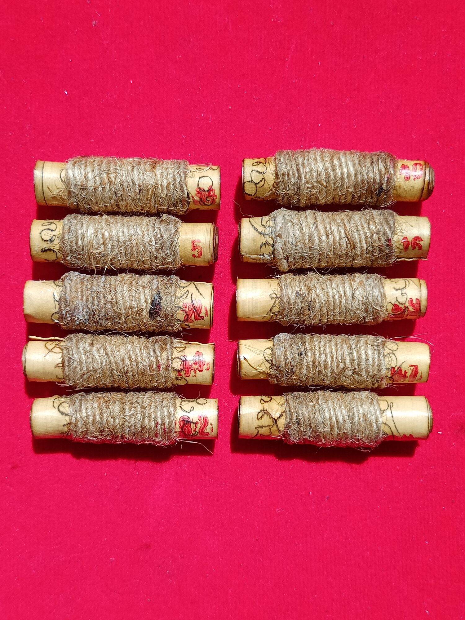 Thai Blessing Co ten cylindrical scroll amulets wrapped in twine on red cloth sacred protection charm for fortune