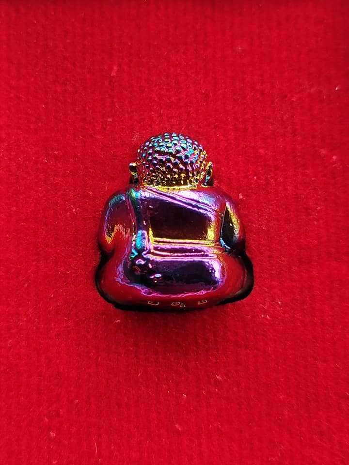Thai Blessing Co Sangkajai Buddha amulet for wealth iridescent metal sitting figurine on red velvet background