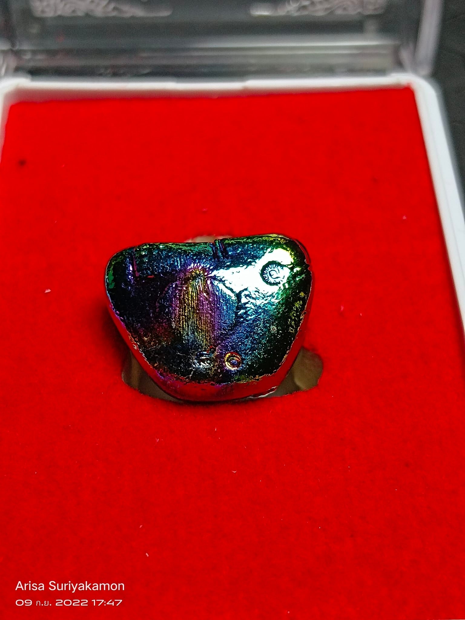 Sangkajai Buddha amulet for wealth iridescent metallic charm on red velvet display tray by Thai Blessing Co