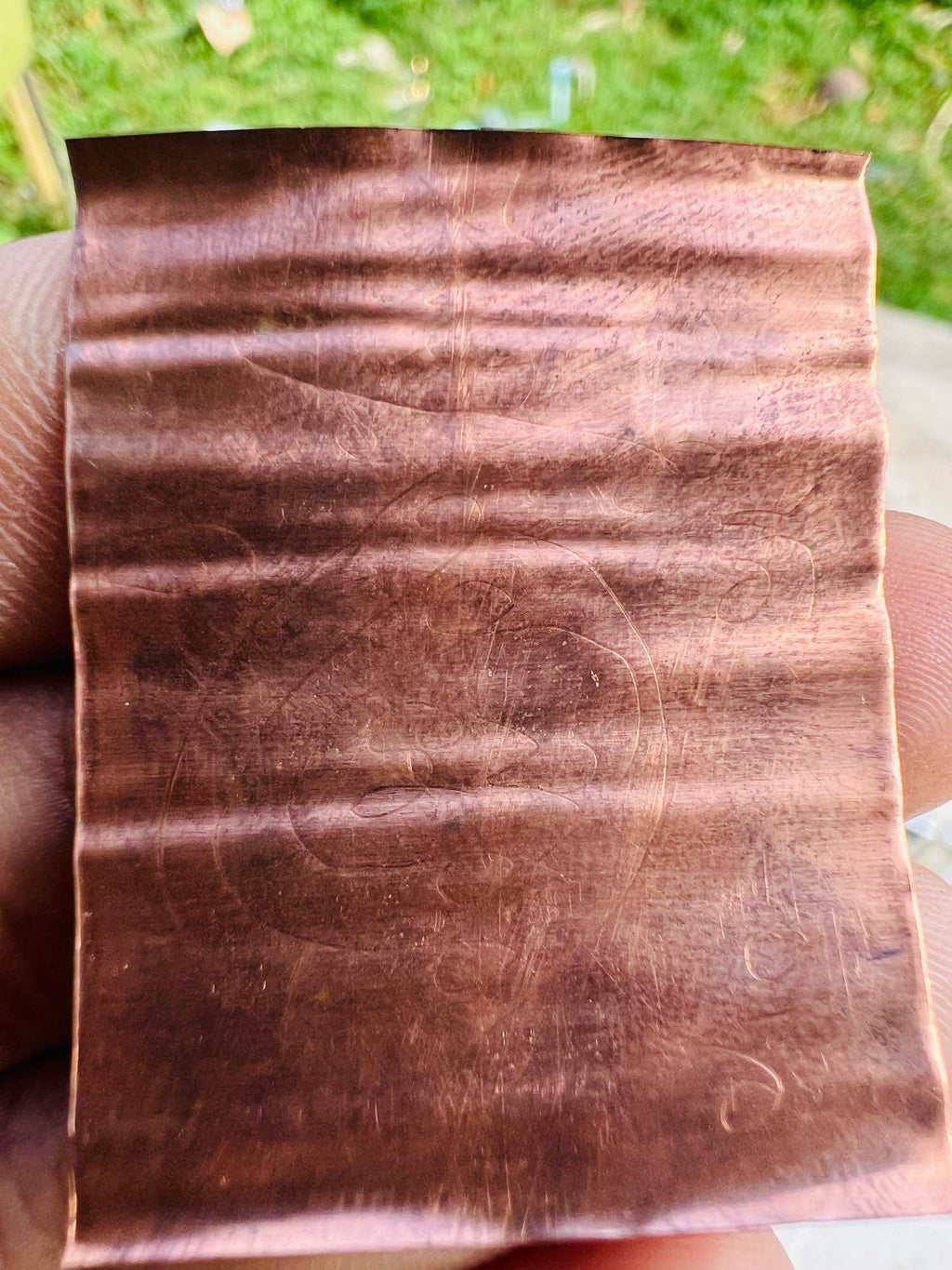 Thai elephant takrud amulet copper sheet pendant with embossed elephant motif held in hand by Thai Blessing Co