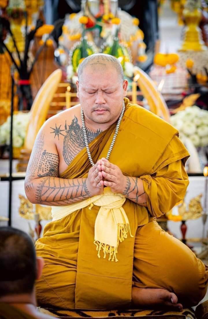 Thai guardian spirit protection charm being blessed by monk with prayer beads during temple ceremony