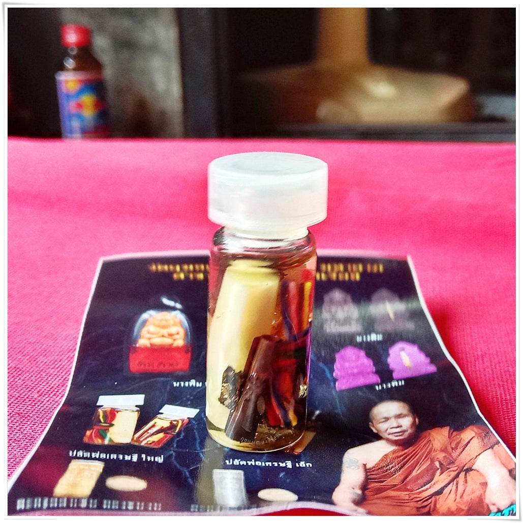 Glass vial amulet with rolled yellow charm and herbs on monk brochure Thai love and fortune talisman