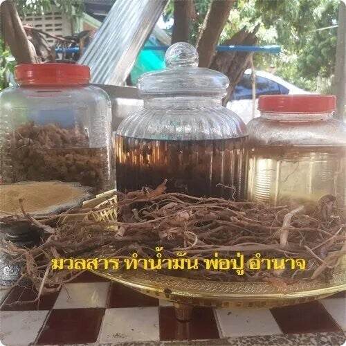 Thai love attraction oil infusion with dried roots and herbs in glass jars on a brass tray by Thai Blessing Co