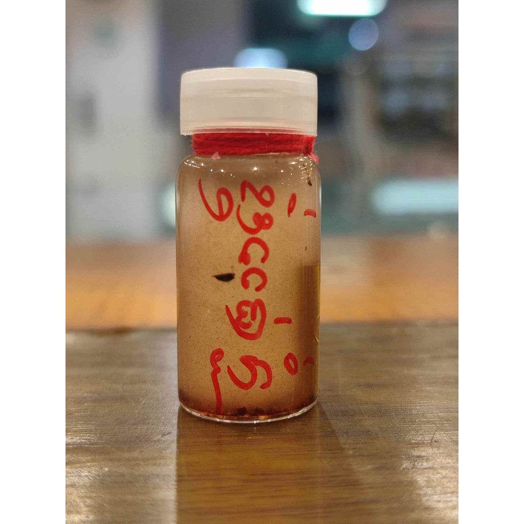 Thai love attraction oil small glass vial with white cap red Thai script amber oil with herbal particulates