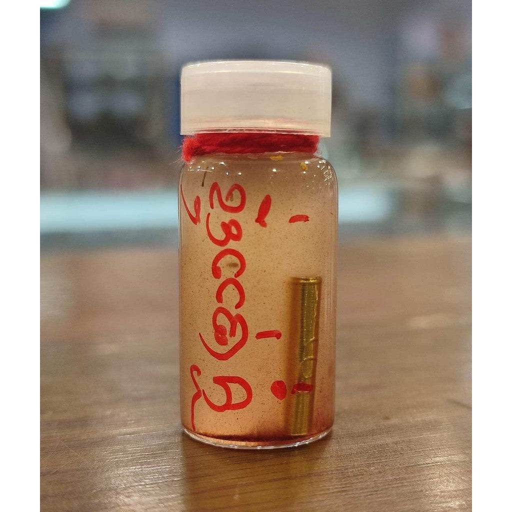 Small Thai Blessing Co bottle of Thai love attraction oil with red script and gold amulet inside