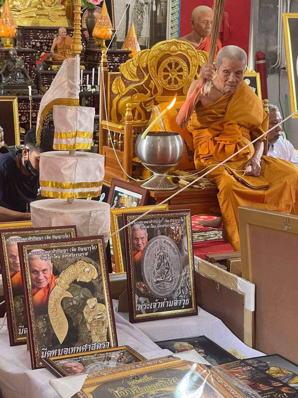 Thai mitmor dagger for protection amulets displayed with framed images and a Buddhist monk blessing ceremony