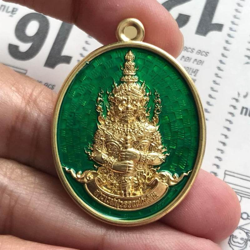 Thai Blessing Co Thao Wessuwan amulet for wealth gold guardian pendant on green enamel background held in hand