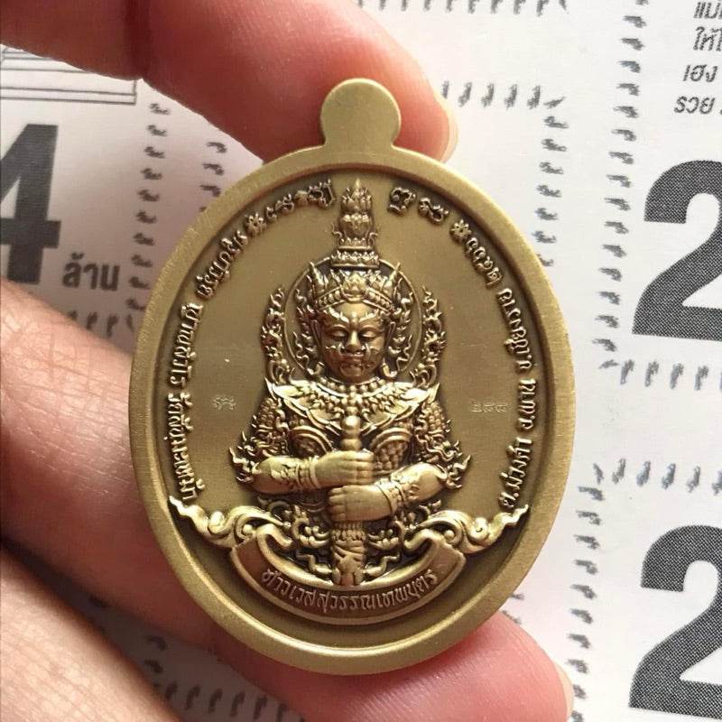 Handheld gold oval Thao Wessuwan amulet for wealth medallion with guardian deity and Thai inscriptions