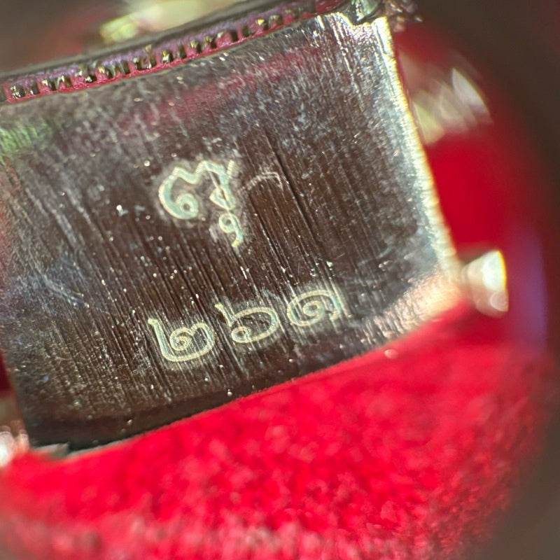 Close up engraving on metal base Thao Wessuwan amulet limited edition with Thai numerals on red velvet