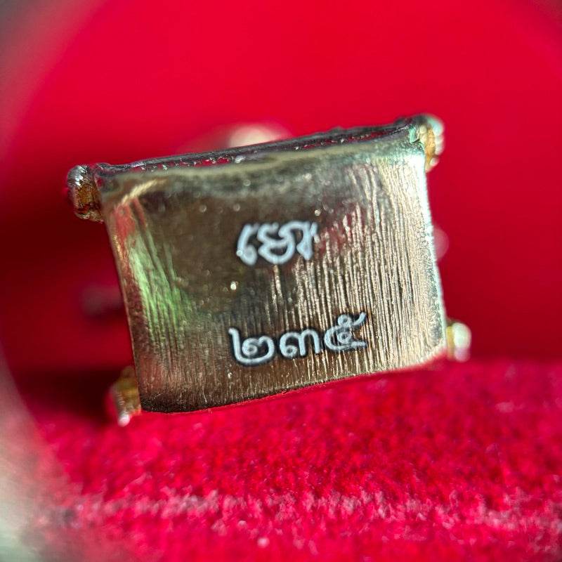 Close up of Thao Wessuwan amulet Wat Suthat brass plaque with engraved Thai numerals on red velvet background