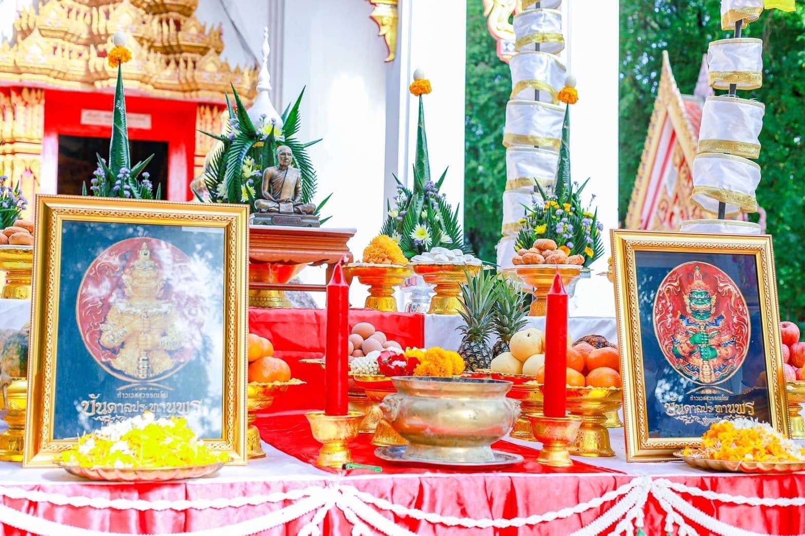 Thao Wessuwanno Bandarn Patthanapon framed amulet display with offerings candles and floral garlands