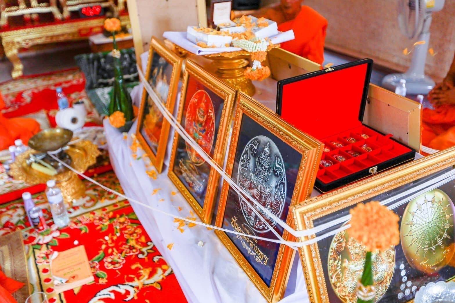 Thao Wessuwanno Bandarn Patthanapon framed amulet plaques in gold frames displayed with ceremonial offerings and red cloth