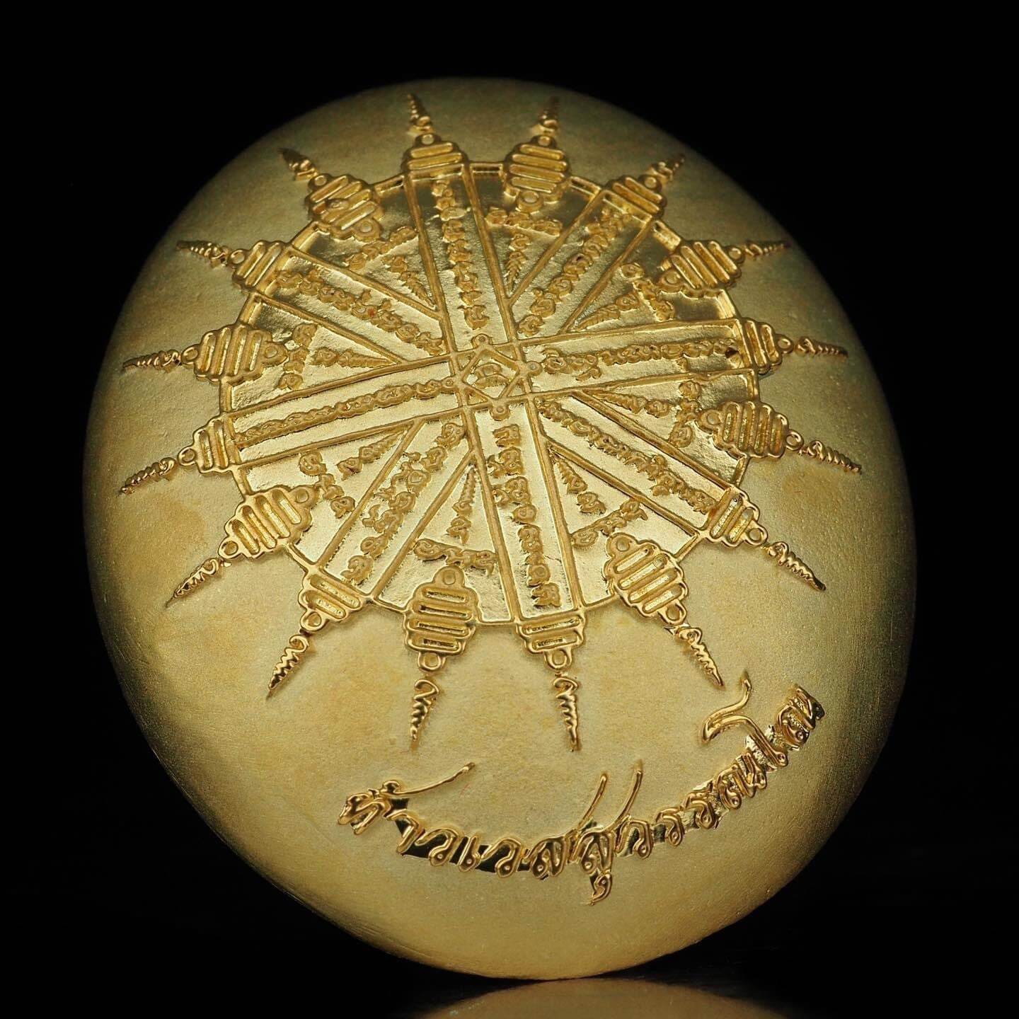 Gold oval amulet with radial spire sun design and Thai script Thao Wessuwanno Bandarn Patthanapon