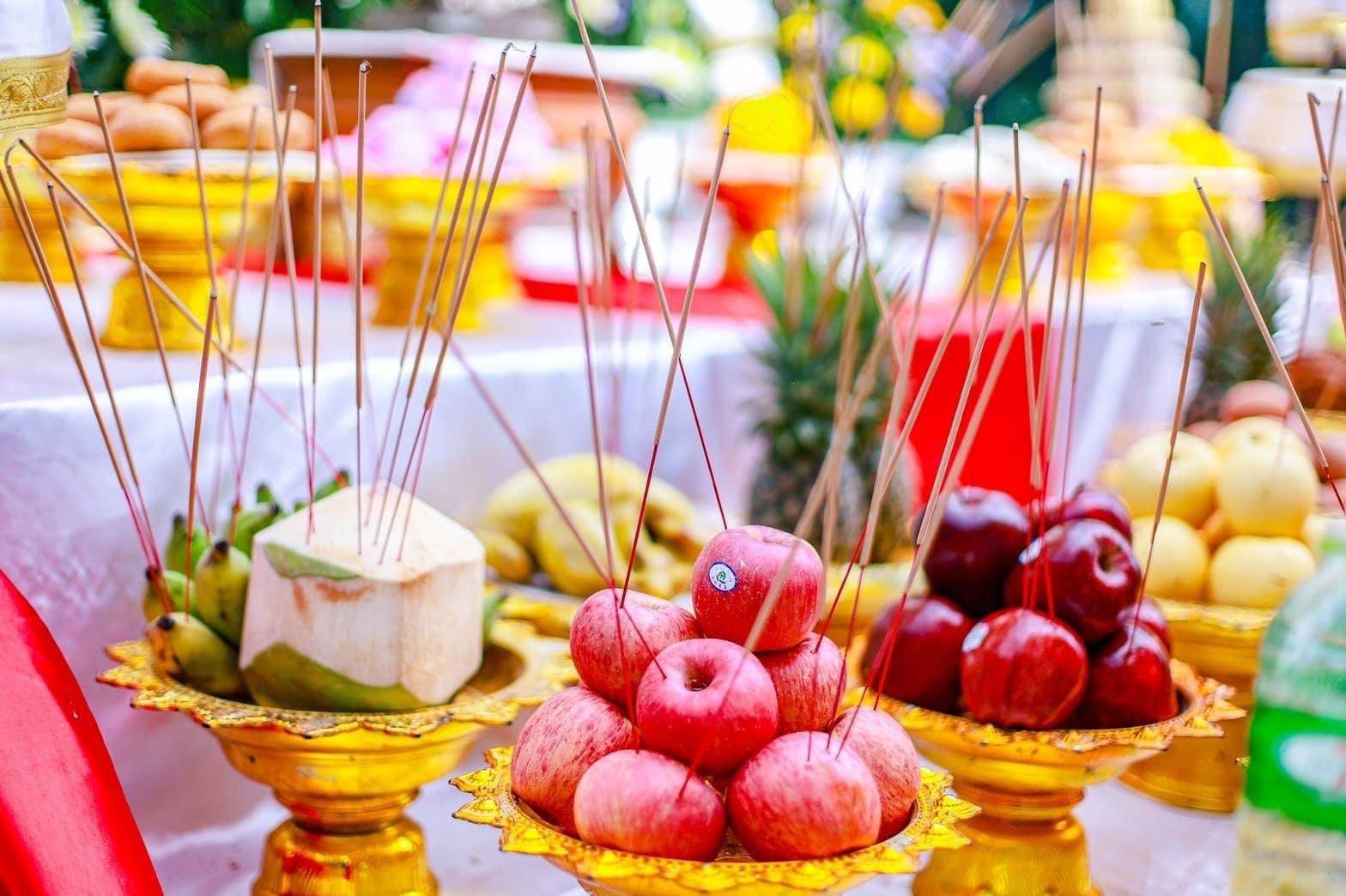 Altar offering with red apples coconuts and incense on golden trays for Thao Wessuwanno Bandarn Patthanapon amulet