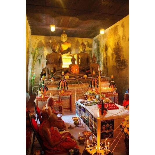 Thai monks blessing Tiger King Takrud amulet for status at temple altar with Buddha statues and offerings