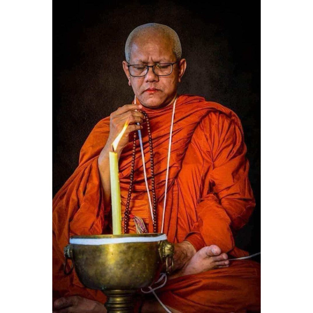 Monk in orange robes praying with beads holding an ancient protection amulet limited edition