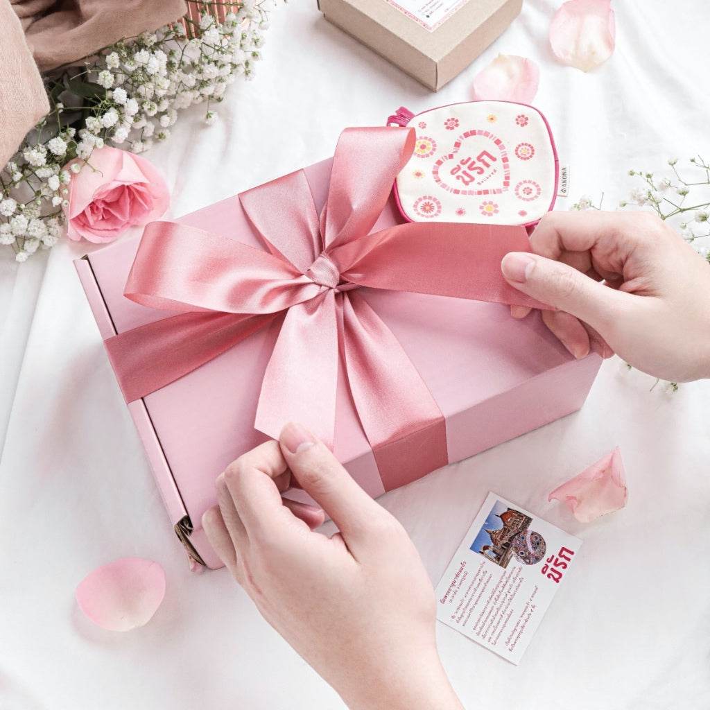 Pink aromatherapy wedding gift box with satin ribbon and floral decorations on white fabric