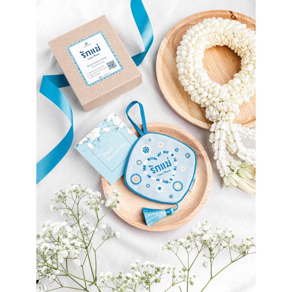 Herbal sachet and diffuser gift for mom with blue packaging and floral garland on wooden plates