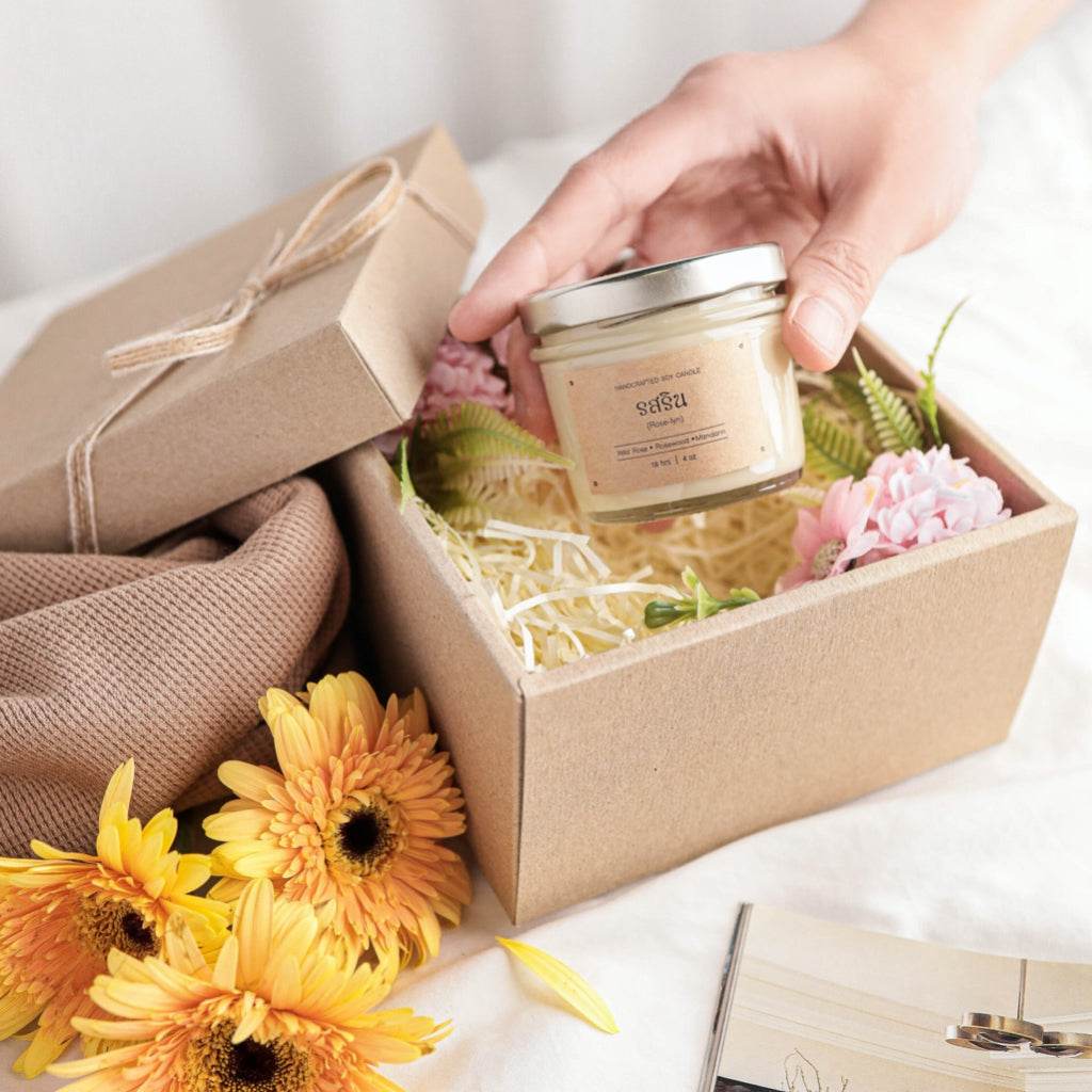 Natural aromatherapy candles in glass jar with metal lid in gift box surrounded by flowers