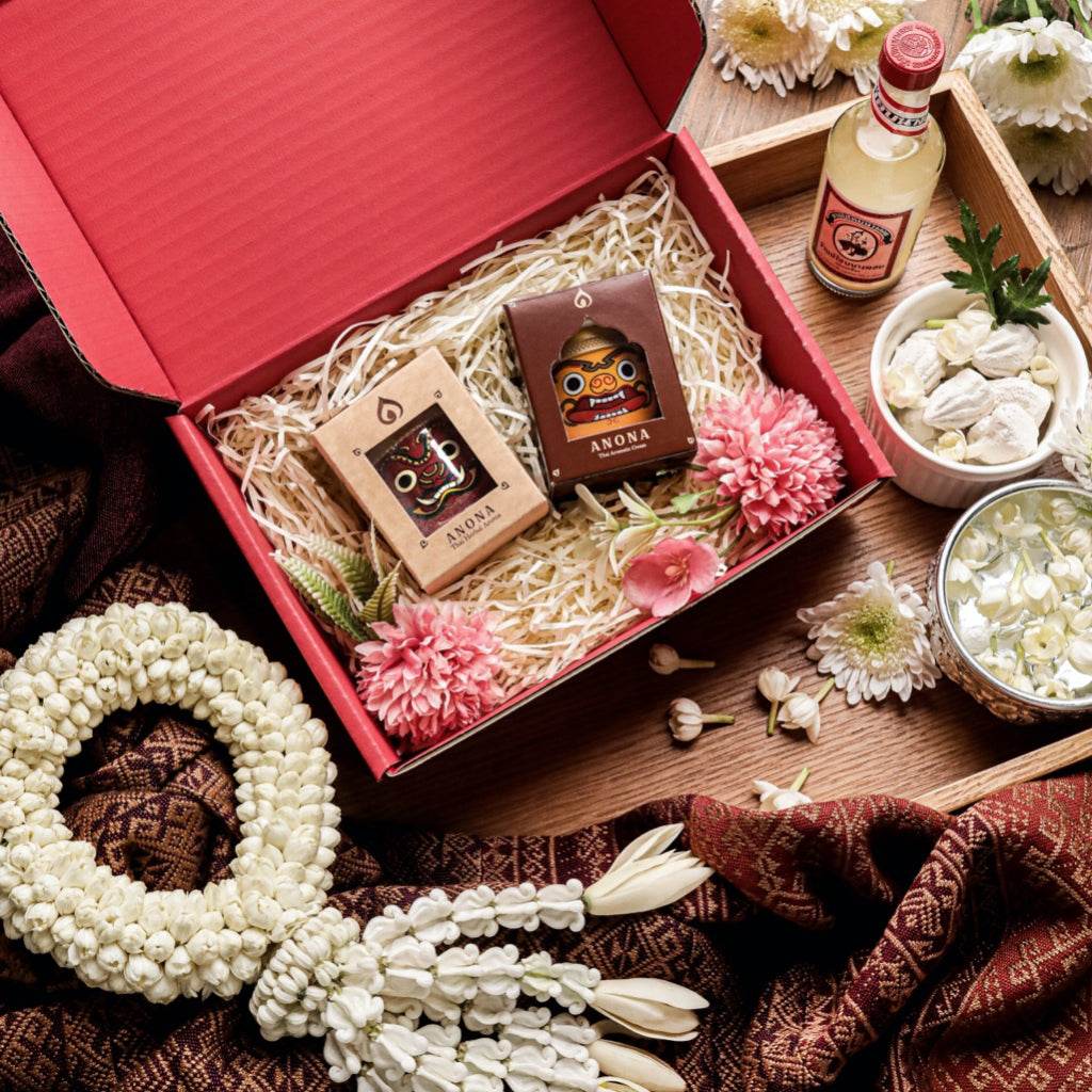 Natural essential oil diffuser set in decorative red box with flowers and aromatic items on wooden tray