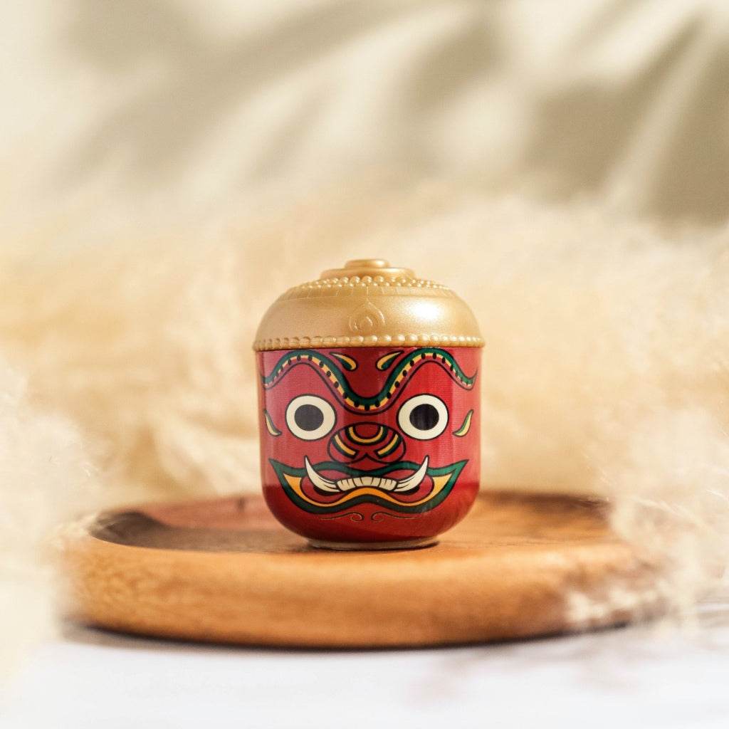 Thai herbal aroma sachet in a decorative red and gold container with traditional mask design