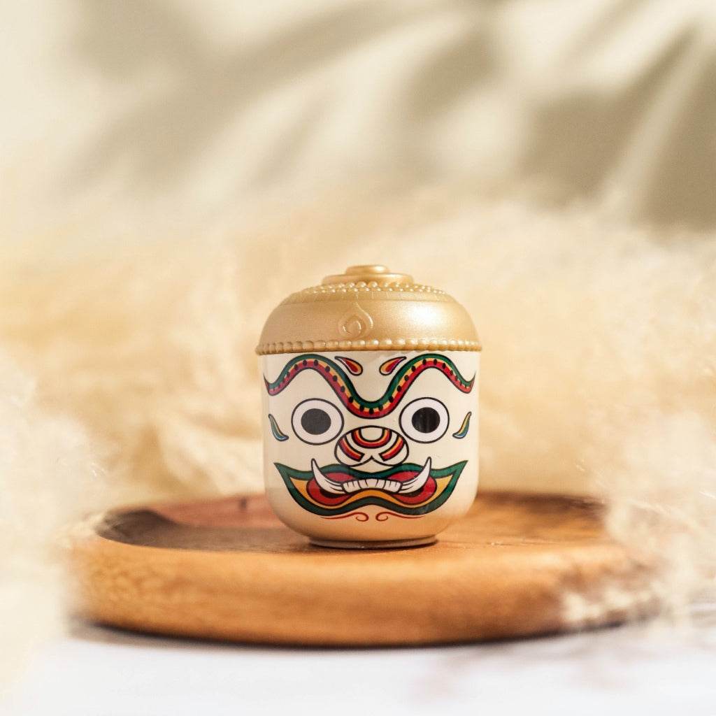 Thai herbal aroma sachet in a decorative container with traditional mask design on wooden tray