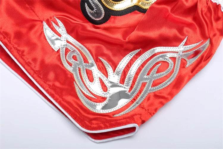 Red satin Muay Thai boxing shorts with silver tribal embroidery white piped trim corner detail