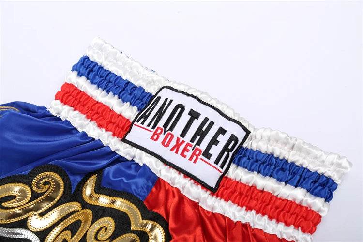 Muay Thai boxing shorts with blue red and white elastic waistband gold ornamental embroidery and brand patch
