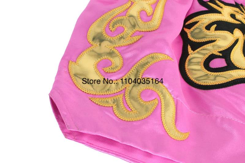 Pink satin kickboxing trunks for men and women with gold embroidered tribal design by Thai Blessing Co