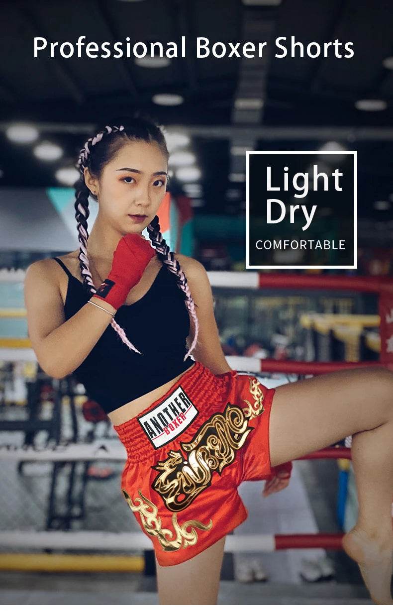 Female athlete in red embroidered Muay Thai shorts unisex with black crop top and red hand wraps in gym