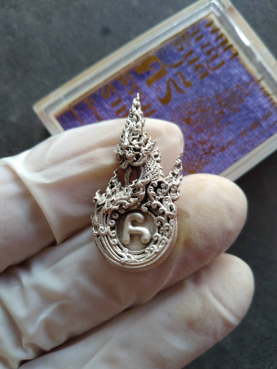 Thai Blessing Co Phaya Naga amulet Thailand silver ornate Naga serpent pendant held in gloved hand