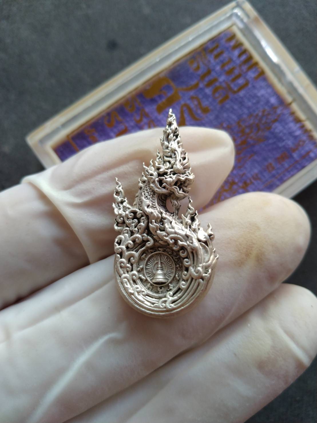 Phaya Naga amulet Thailand silver pendant with intricate flame Naga design held in gloved hand