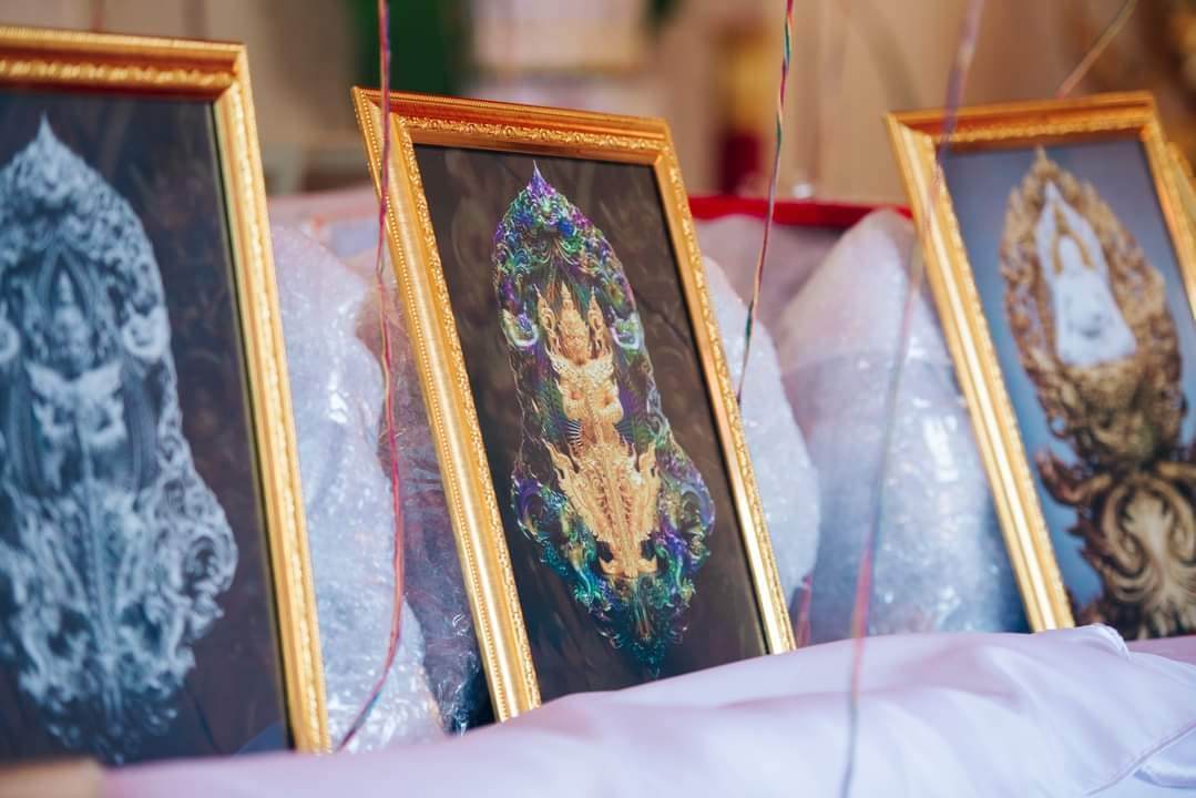 Framed authentic Thai blessed amulet with intricate designs displayed in gold frames on a soft surface