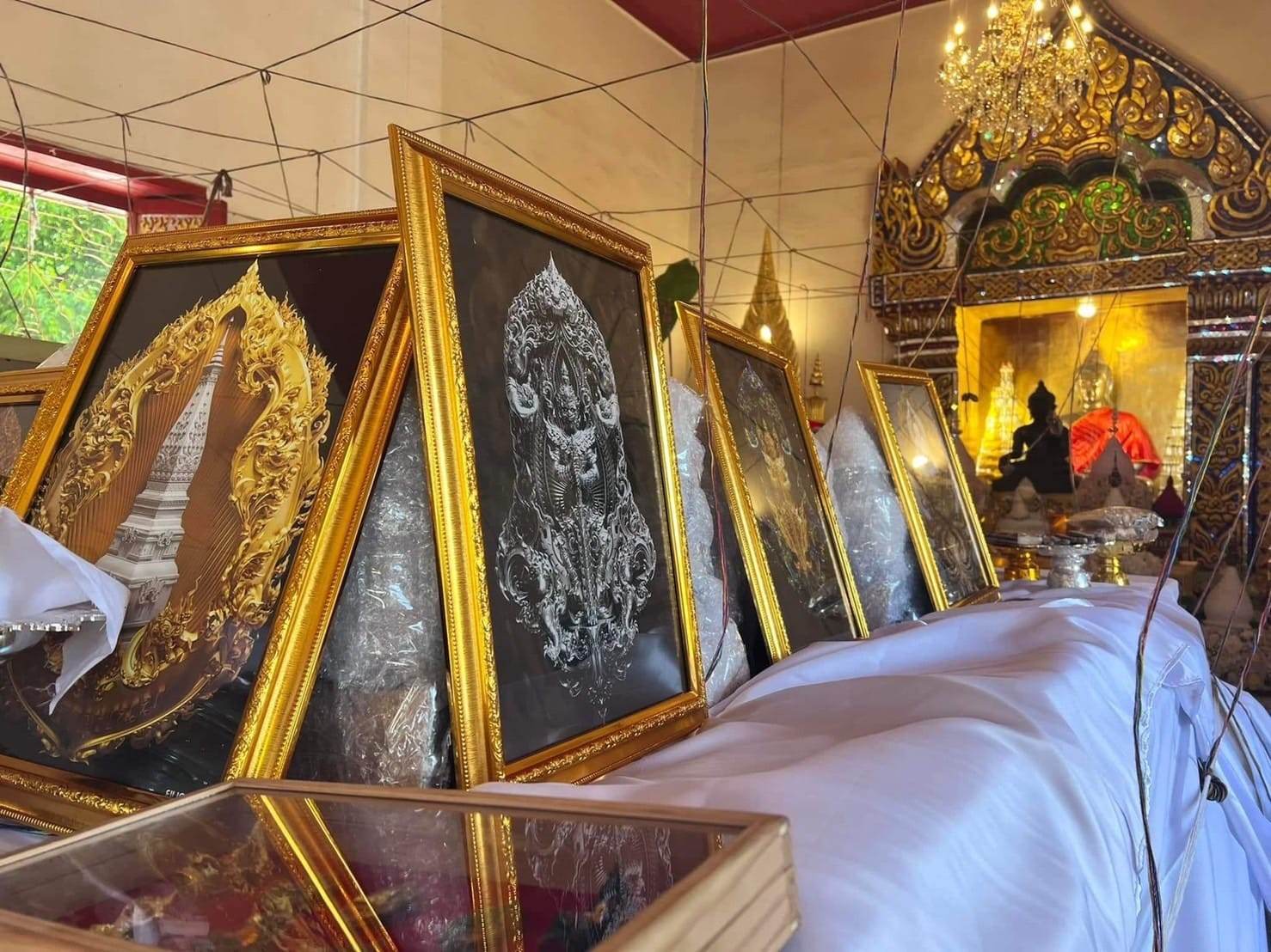 Framed authentic Thai blessed amulet artwork displayed in a traditional temple setting with ornate golden decor