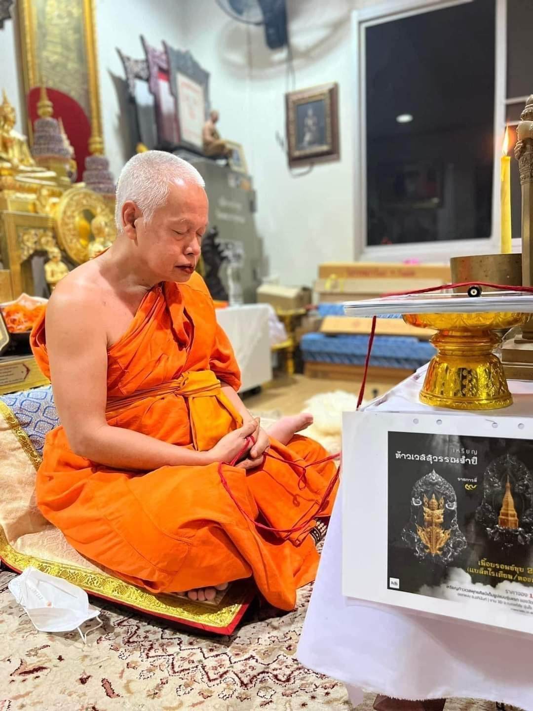 Monk meditating beside golden altar holding authentic Thai blessed amulet in temple setting
