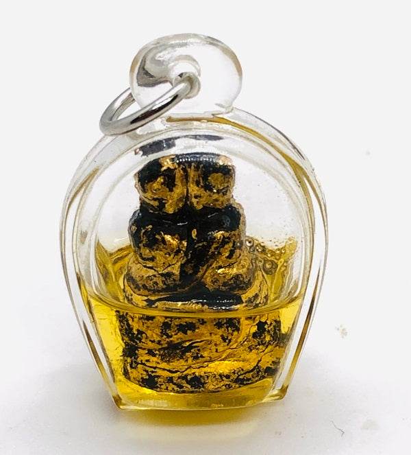 Authentic Thai blessing amulet in a clear pendant with golden accents and protective casing