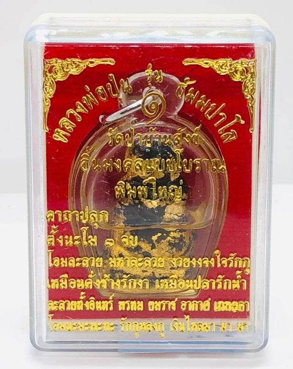 Authentic Thai blessing amulet in glass display with ornate red and gold design for spiritual protection