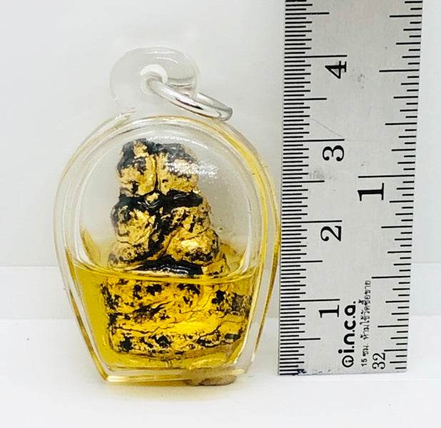 Authentic Thai blessing amulet encased in clear plastic with a gold finish and measuring ruler for size reference