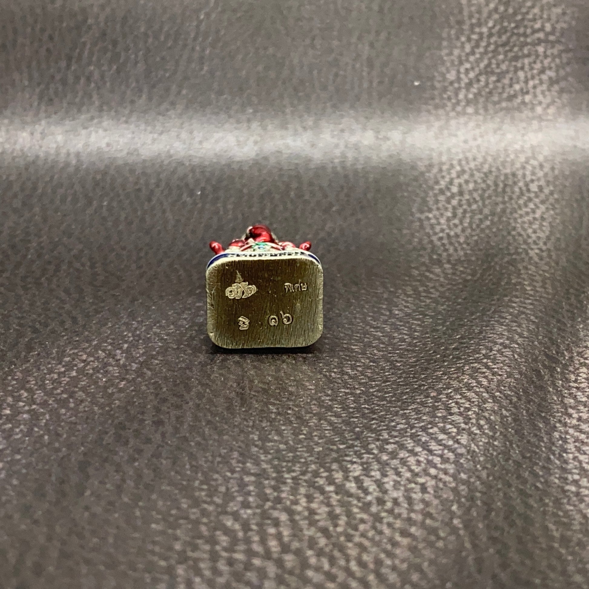 Authentic Thai Ganesha amulet with detailed engraving and decorative red accents