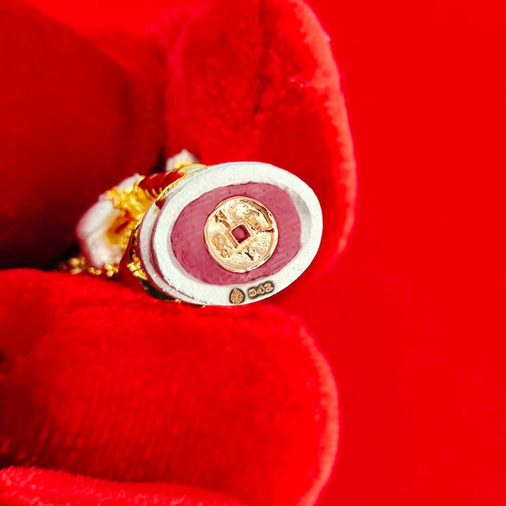 Authentic Thai protective amulet held in a red glove showcasing its intricate design and craftsmanship