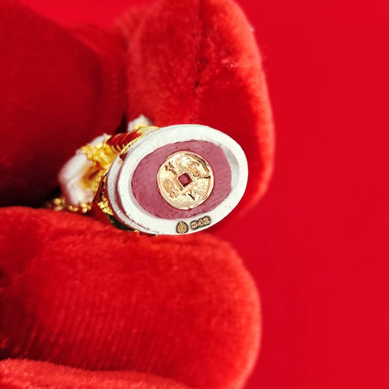 Authentic Thai protective amulet held in a red velvet glove showcasing intricate details