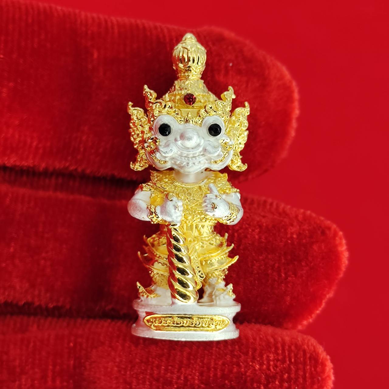 Authentic Thai protective amulet featuring a detailed gold and white figure with intricate designs