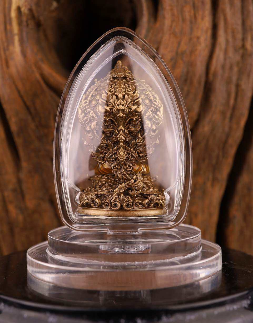 Phra Nak Prok statue bronze amulet in clear plastic display case on tiered acrylic stand with wood backdrop