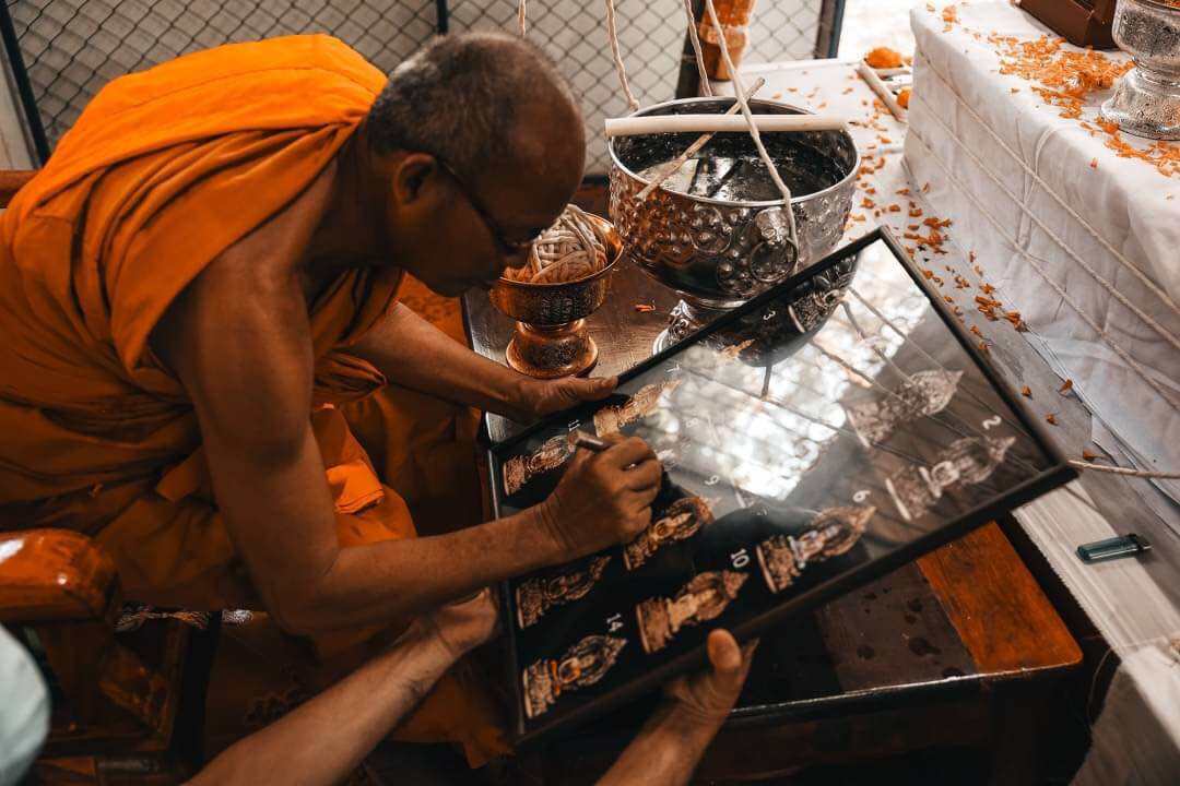 Thai monk blessing Phra Nak Prok statue bronze amulets in framed display for pendant talismans