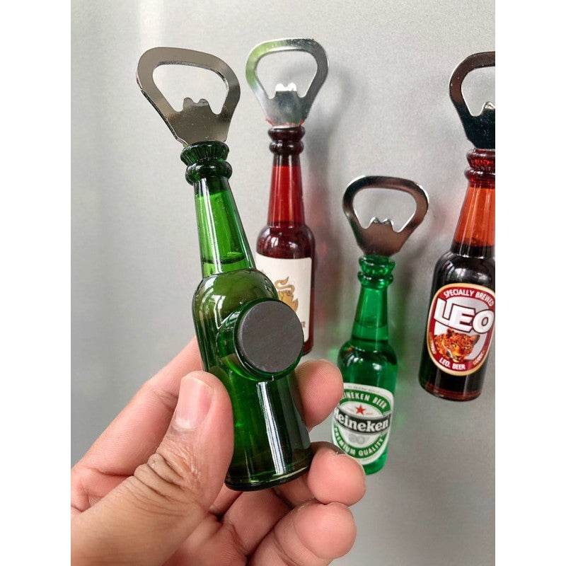 Beer bottle opener fridge magnet shaped like a green Heineken beer bottle held in hand with other bottle opener fridge magnets on wall
